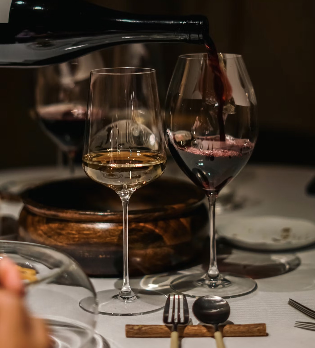 Pouring red and white wine at a table setting