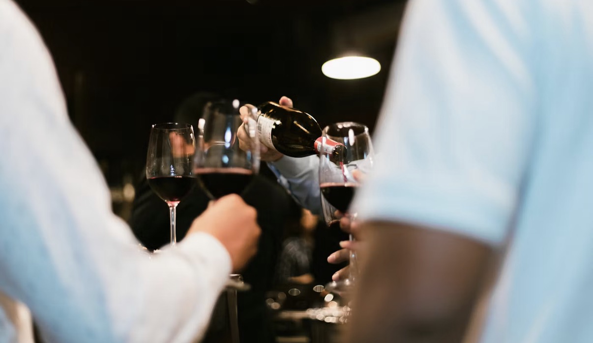 Pouring wine at a toast, glasses raised